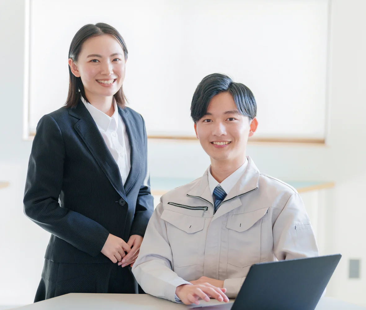 スーツと作業着姿で笑顔の2人のスタッフ